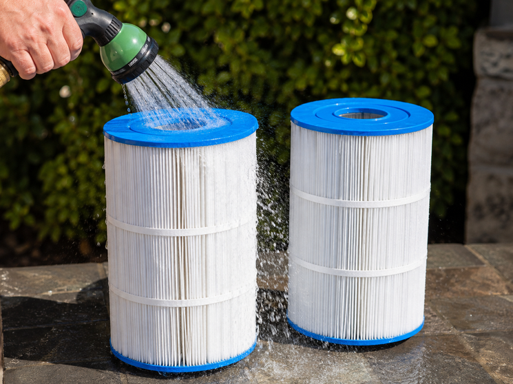 Photo of two cartridges being rinsed with a hose.